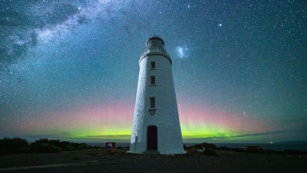 Aerial view of Cape Bruny Lighthouse under the Milky Way and Aurora Australis in Tasmania.